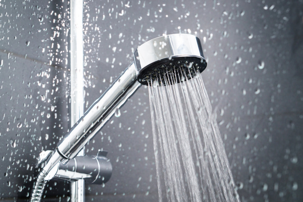 Shower head spraying water in wet shower enclosure