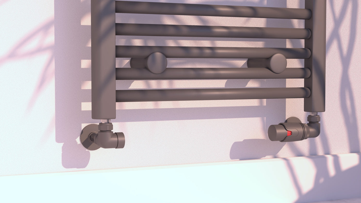 Anthracite corner valve set connecting wall pipework to a heated towel rail above a white skirting board, with plant shadows.