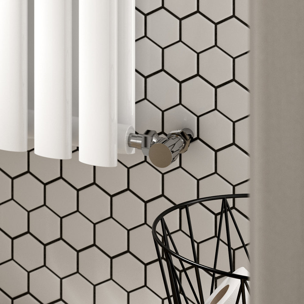 Manual radiator valve attached to white radiator on tiled wall