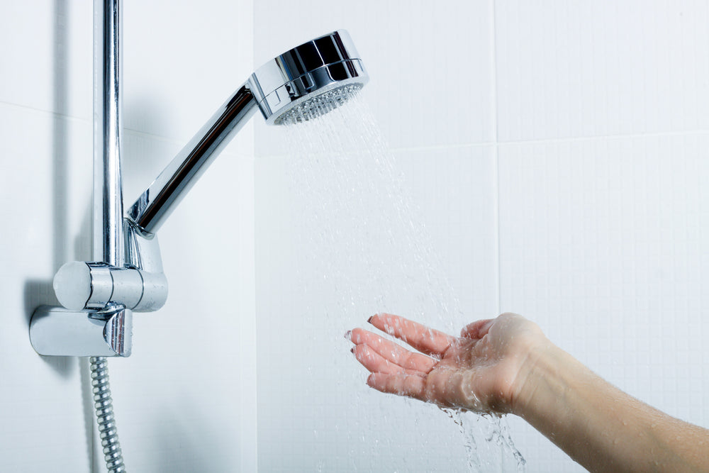 Person estimating their low water pressure using water coming out of their shower head